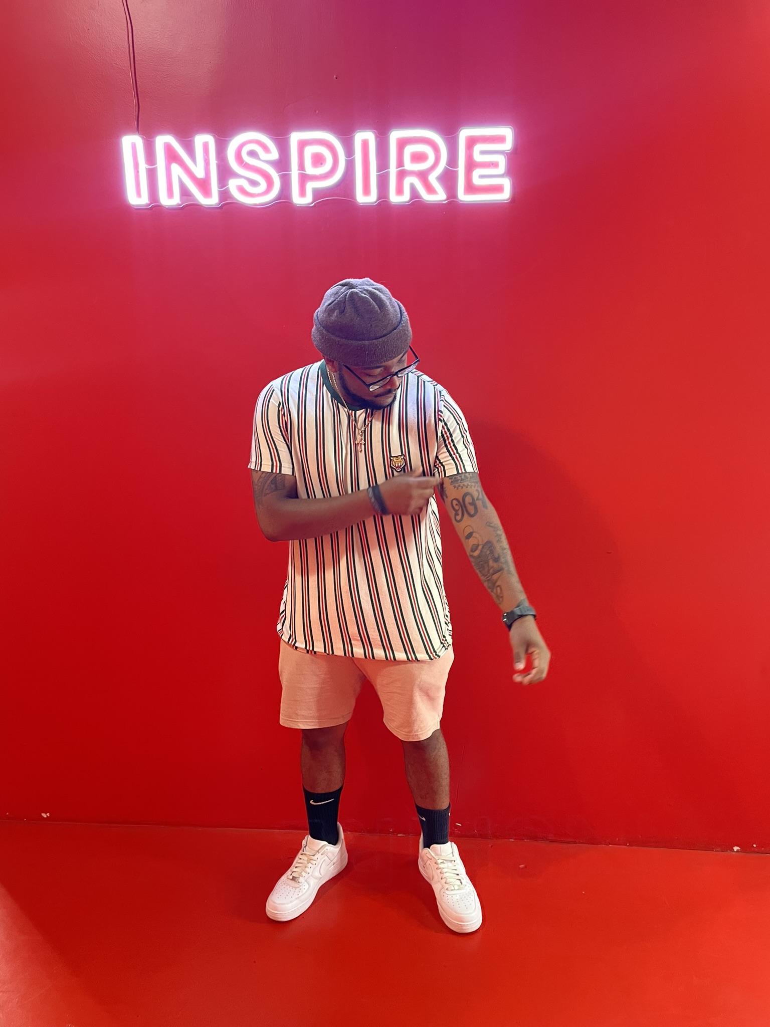  Posing with head down, with left arm out,under the LED lit word inspire.