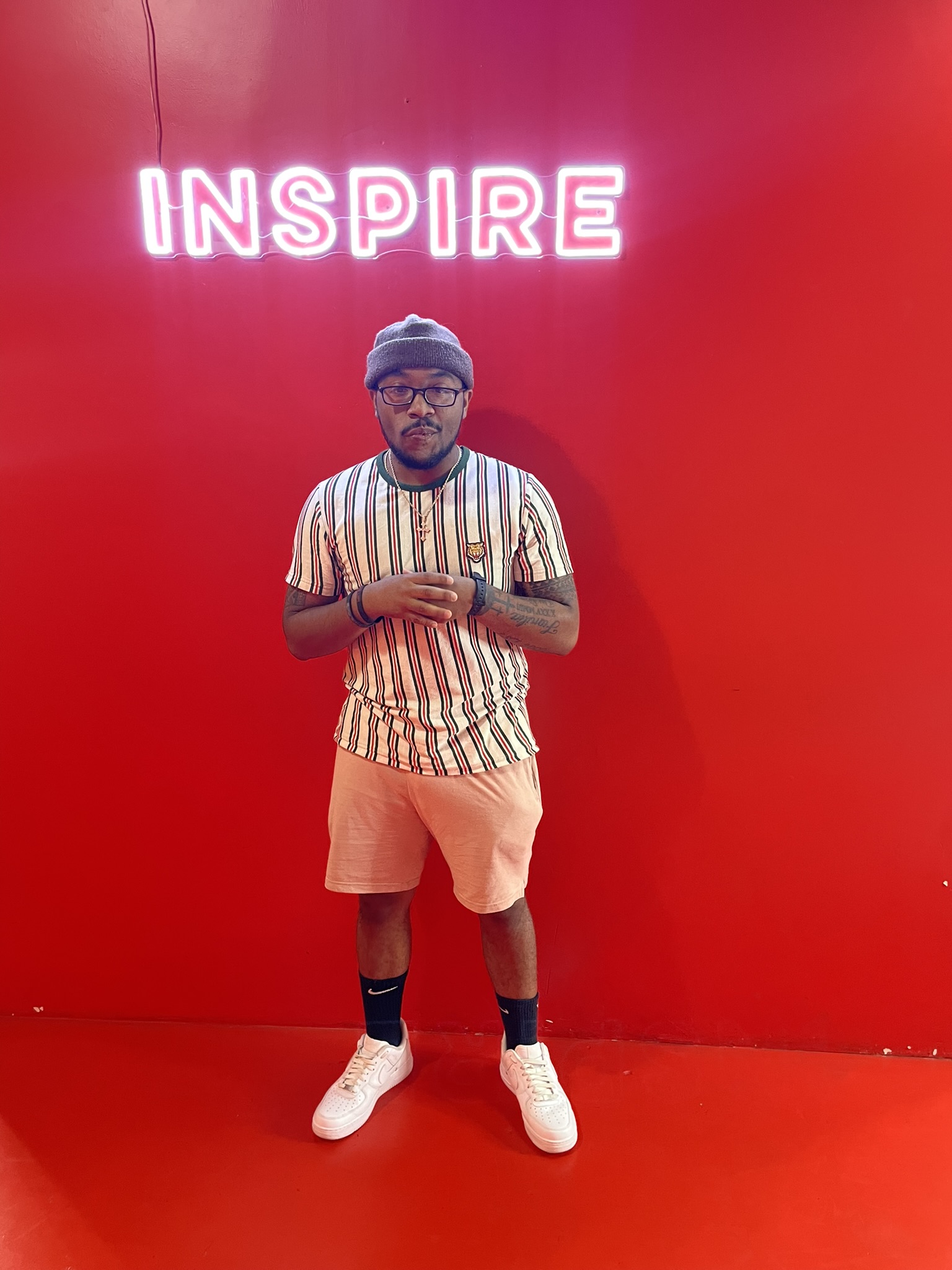  Posing under the LED lit word inspire, with hands together and looking forward at the camera.