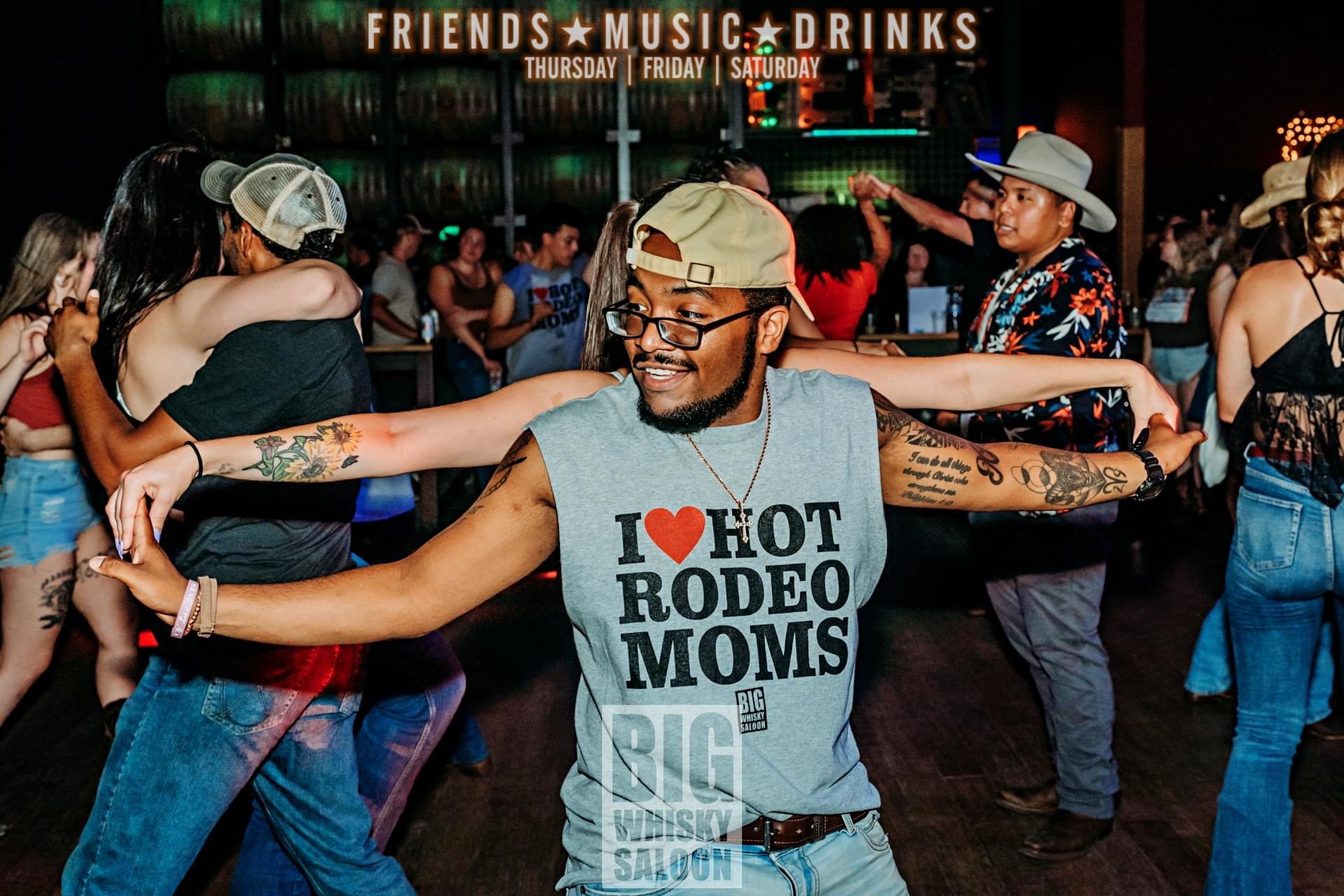 Miggy posing infront of camera with both arms extended out while in the middle of a partner dance.