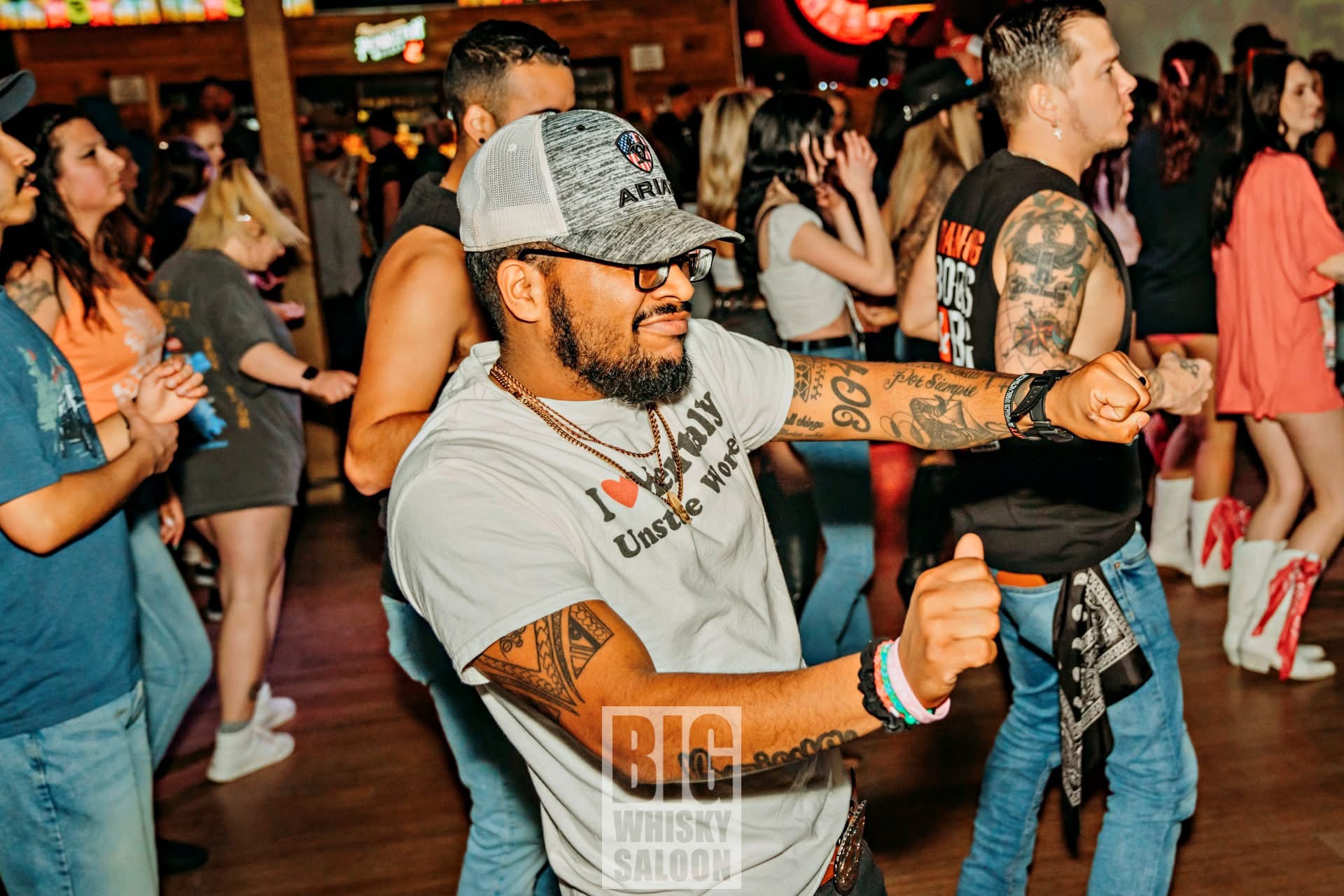 Miggy dancing and has his arms extended out during a linedance.